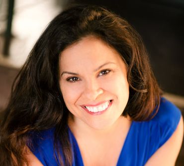 Woman with long dark hair, smiling, wearing a blue top.