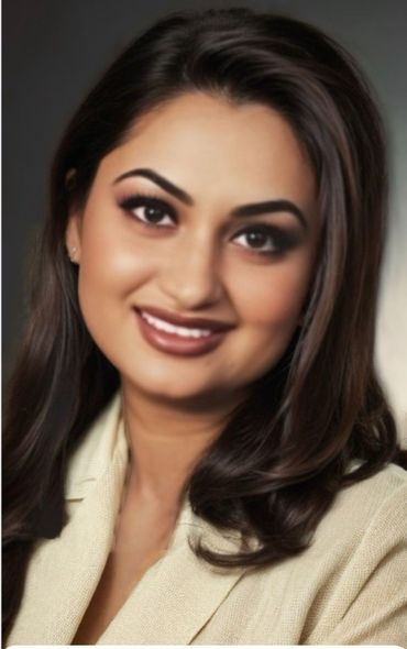 Woman with dark hair smiles, wearing a cream blazer.