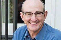 Smiling man wearing glasses and a blue shirt.