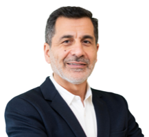 Man in a navy blazer and white shirt smiles at the camera against a white backdrop.