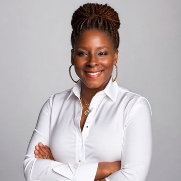 Woman with arms crossed, smiling, wearing white shirt, hoop earrings, and necklace. Braided hair in a bun.