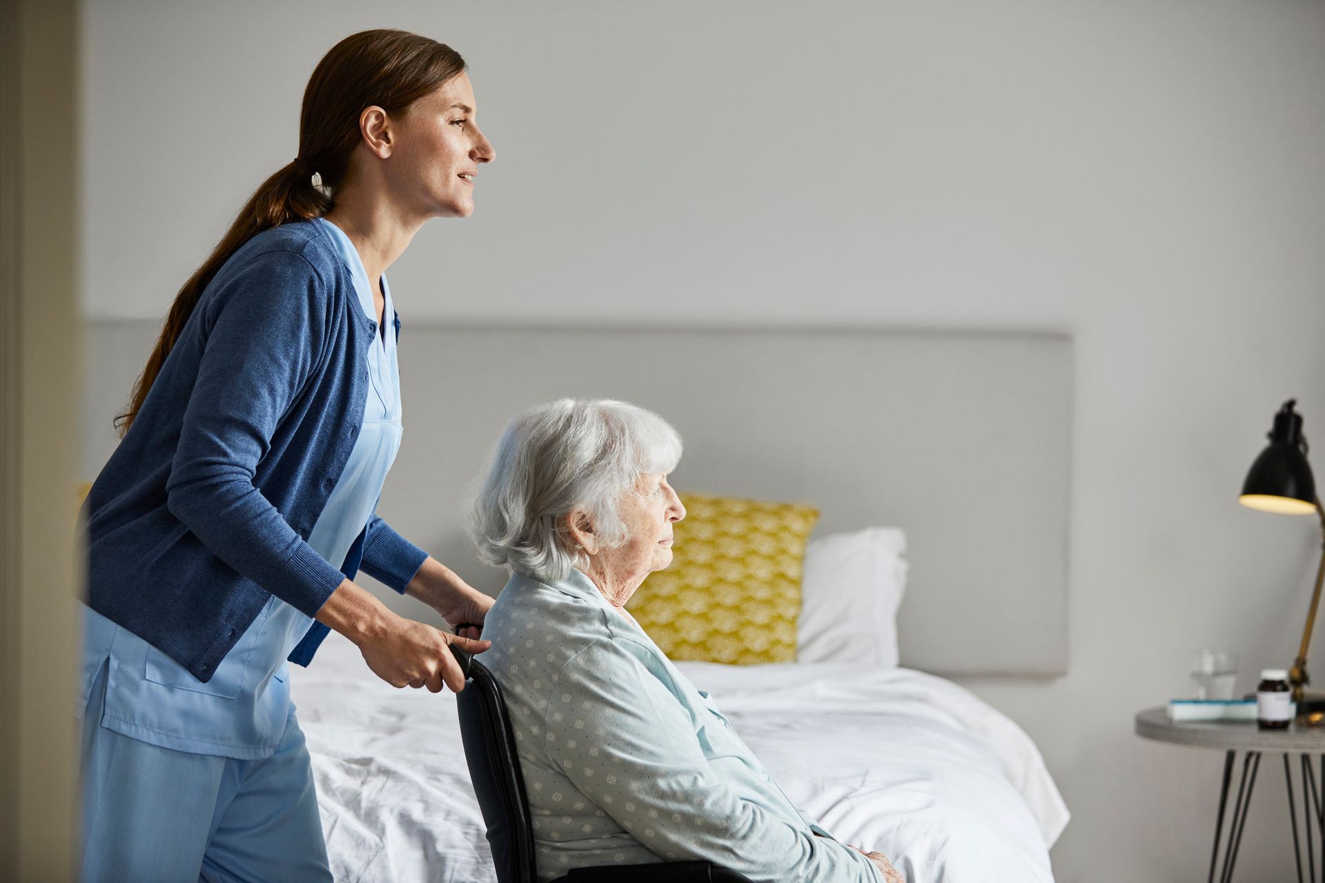 Certified Nurse Practitioner caring for elderly woman in wheelchair at home, offering warm support. Certified Nurse Practitioner caring for elderly woman in wheelchair at home, offering warm support.