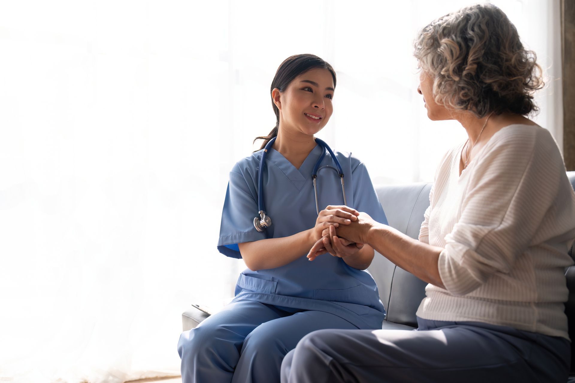 Certified Nurse Practitioner holds elderly patient’s hand, smiling, showing compassion. Certified Nurse Practitioner holds elderly patient’s hand, smiling, showing compassion.