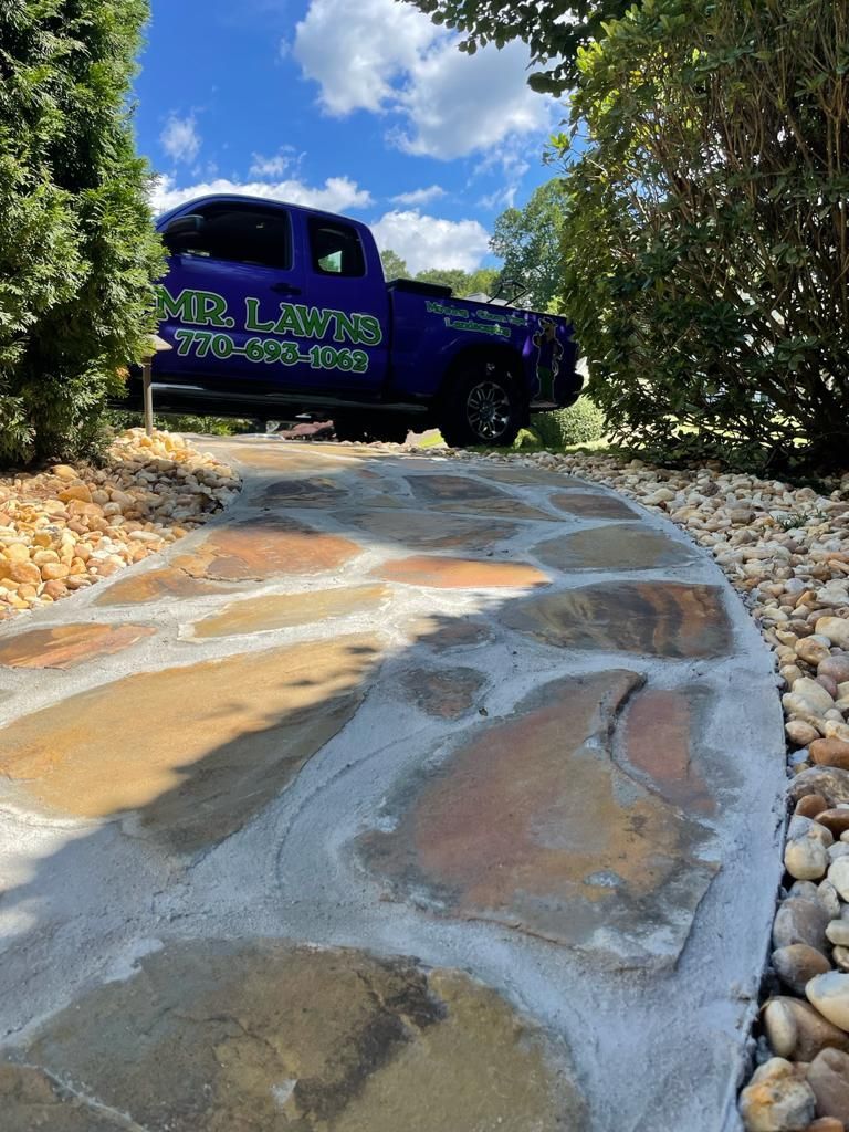 Stone pathway leading to a purple truck with business logo on a sunny day.