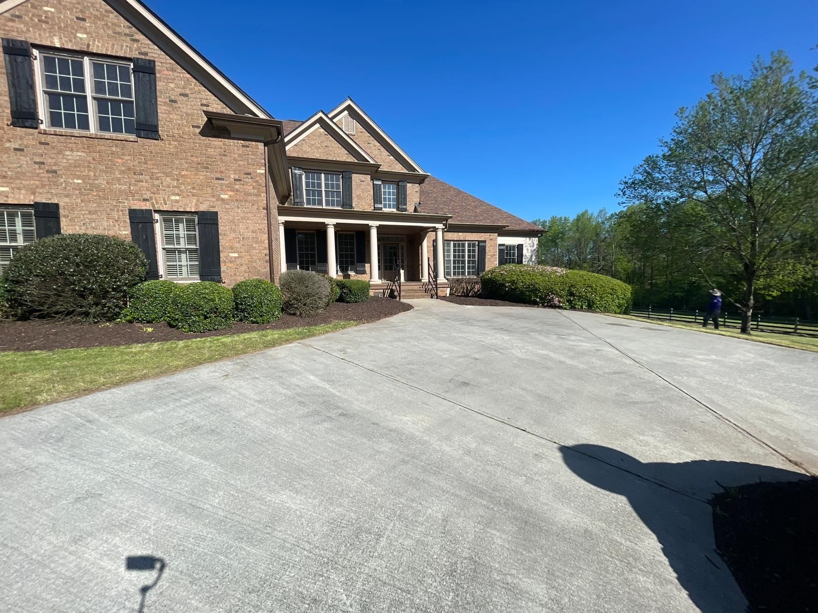 A brick house with a curved driveway on a sunny day.