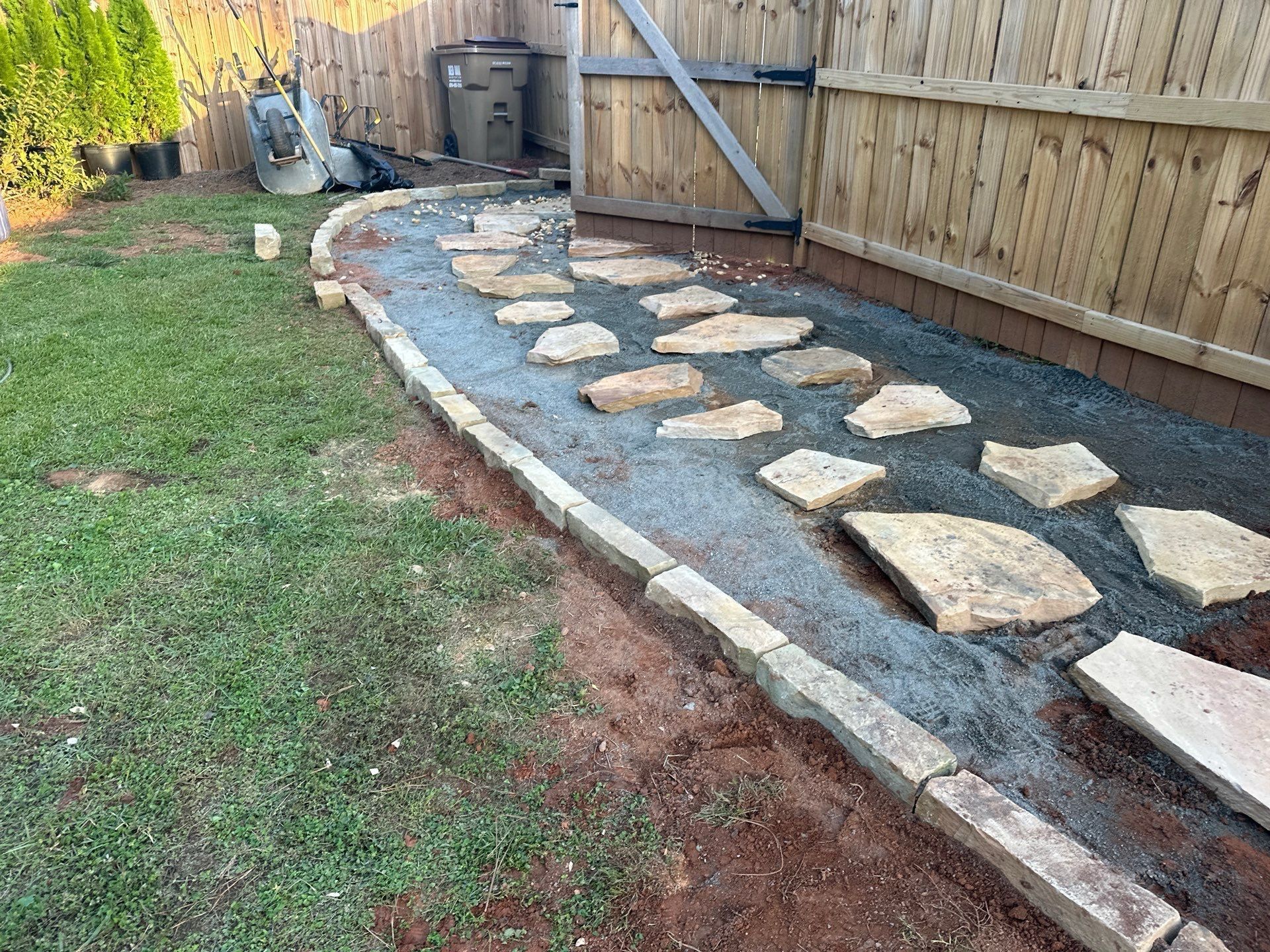 Stone path with stepping stones, gravel, and brick border in a backyard setting.