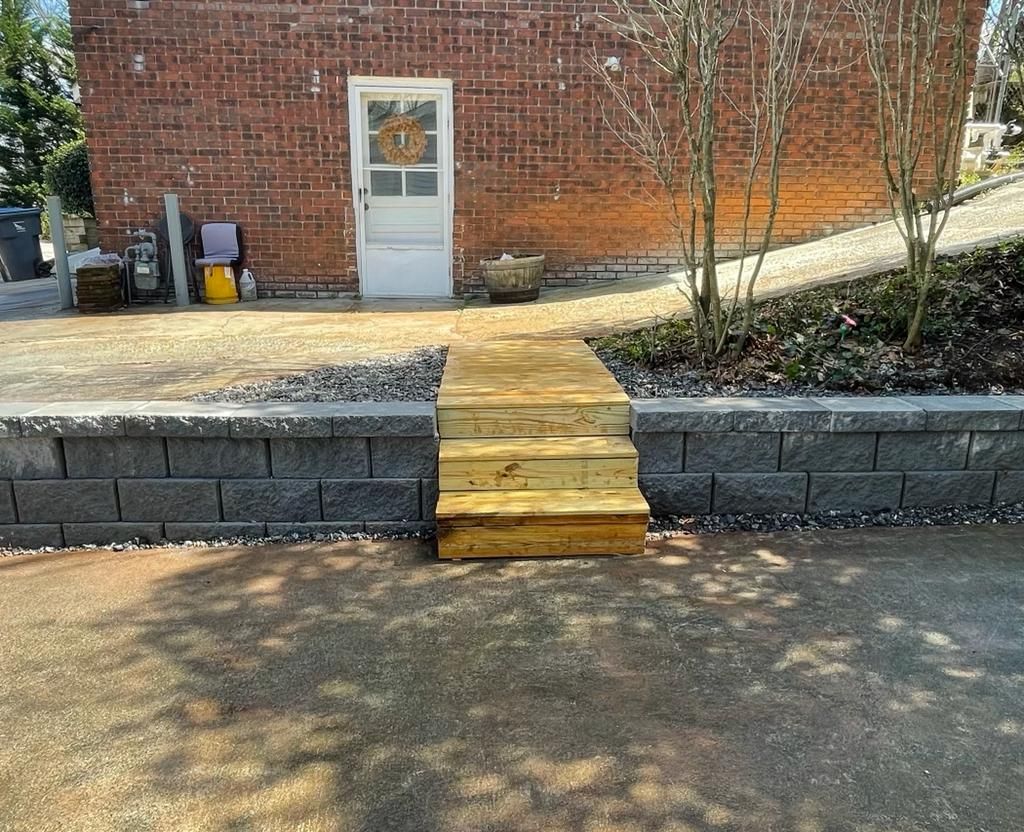 Brick building with retaining wall and wooden steps leading to a back door.