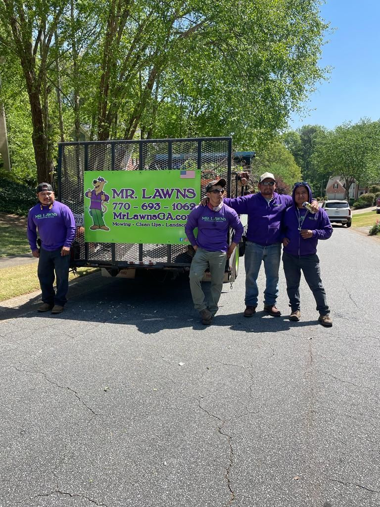 Four people in purple shirts stand in front of a trailer with a 