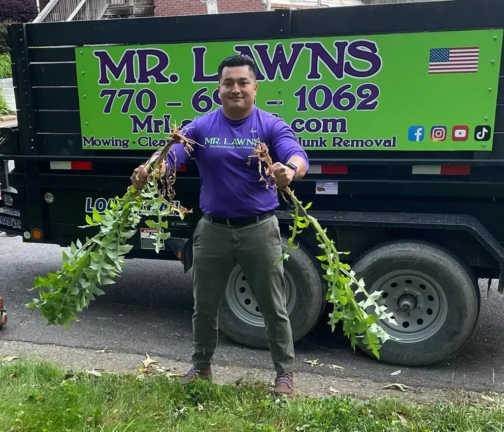 Man holding leafy vines stands in front of a trailer with 