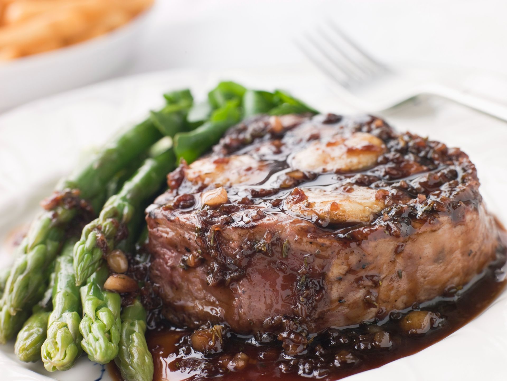 Grilled steak with asparagus and sauce on a white plate