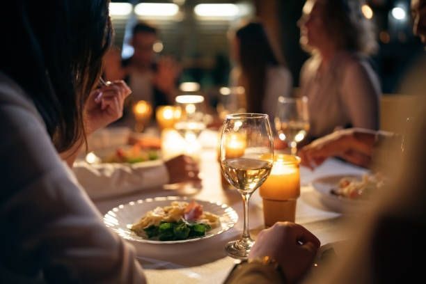 People dining at a warmly lit restaurant table with wine glasses and candles