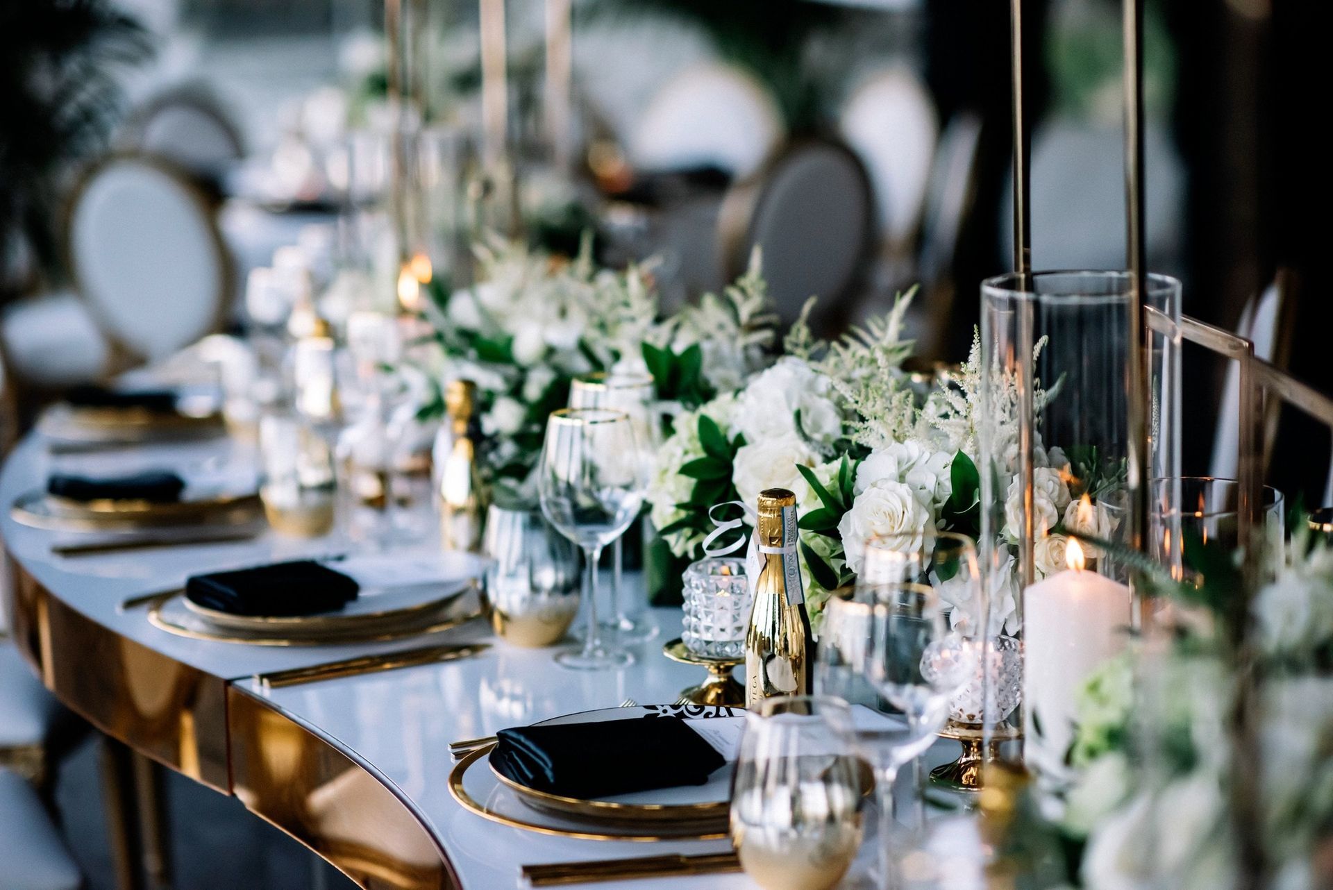 Elegant banquet table with white floral centerpieces, gold accents, and neatly set place settings