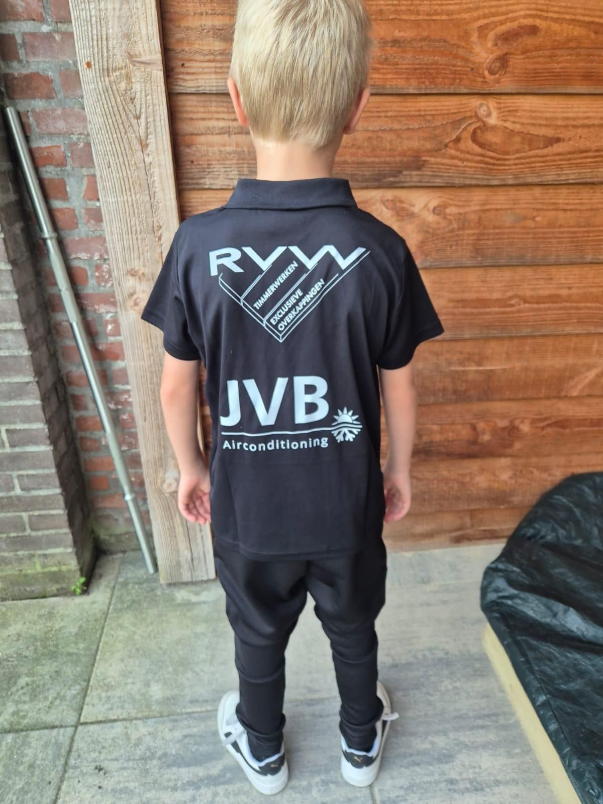 Een kind in een zwart uniform met een logo op de rug staat op een terras.