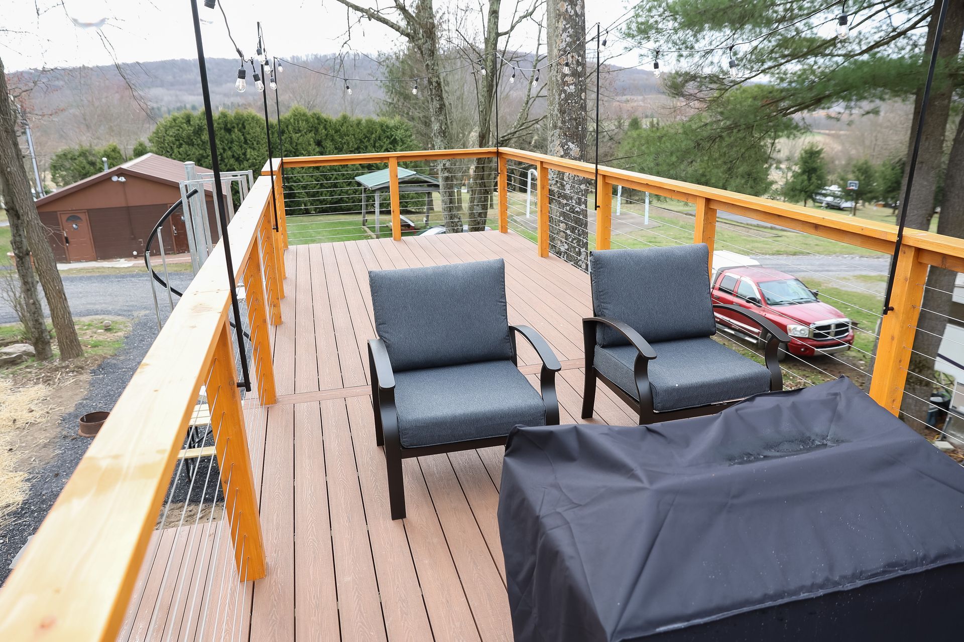 A wooden deck with chairs and a grill on it