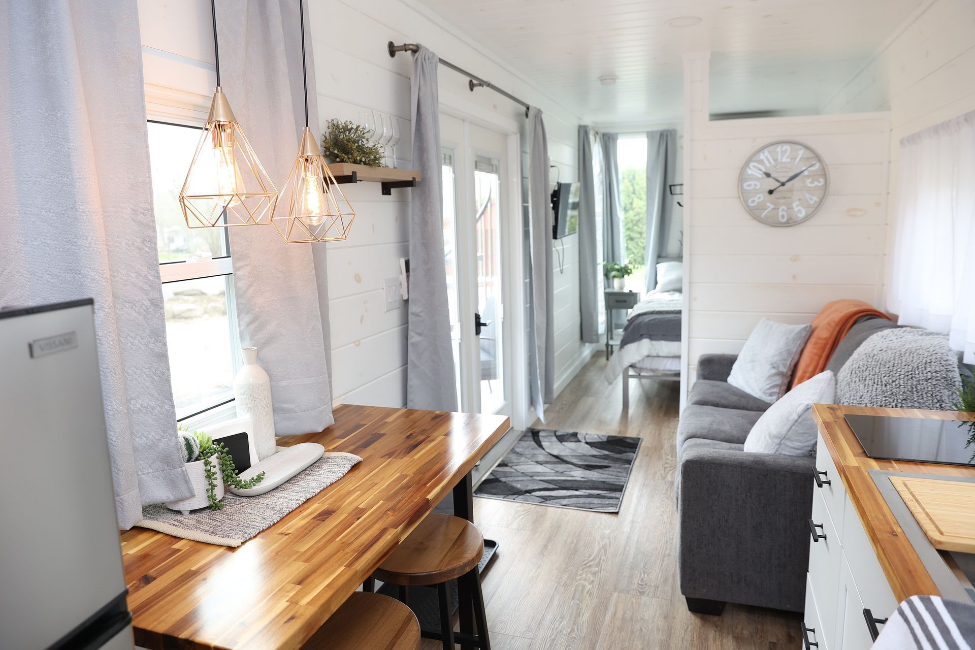 A living room with a couch , table and a clock on the wall.