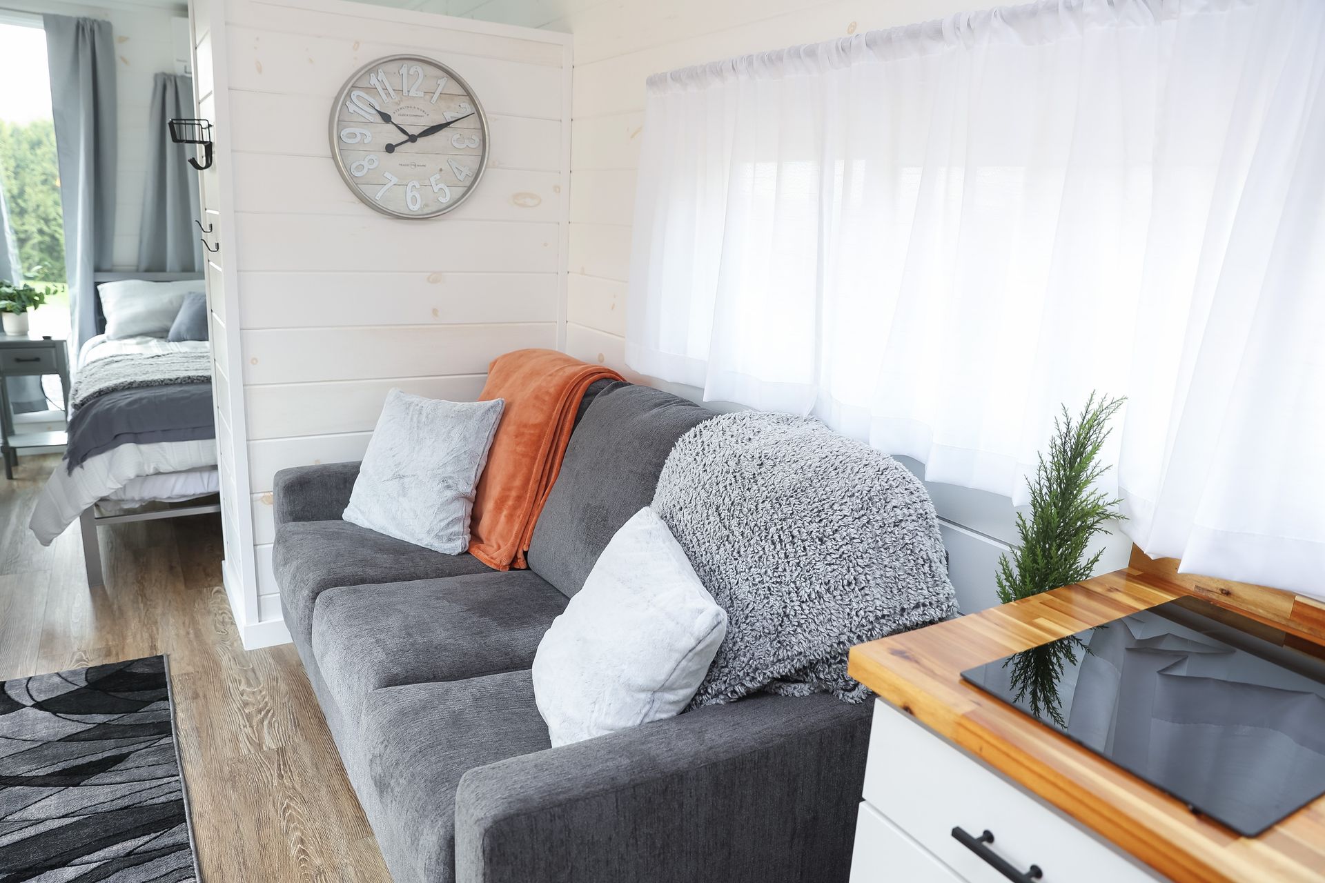 A living room with a couch and a clock on the wall.
