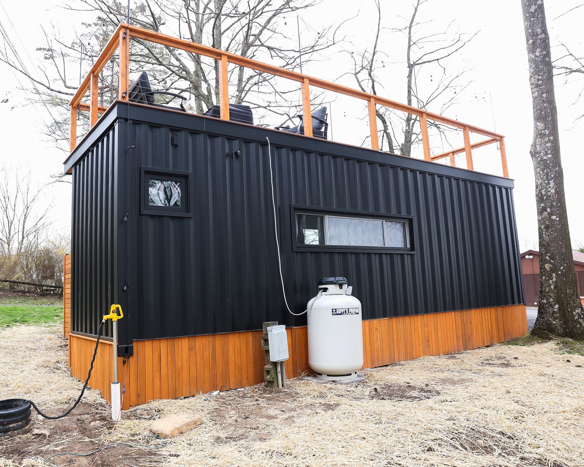 A black building with a propane tank on the side of it.