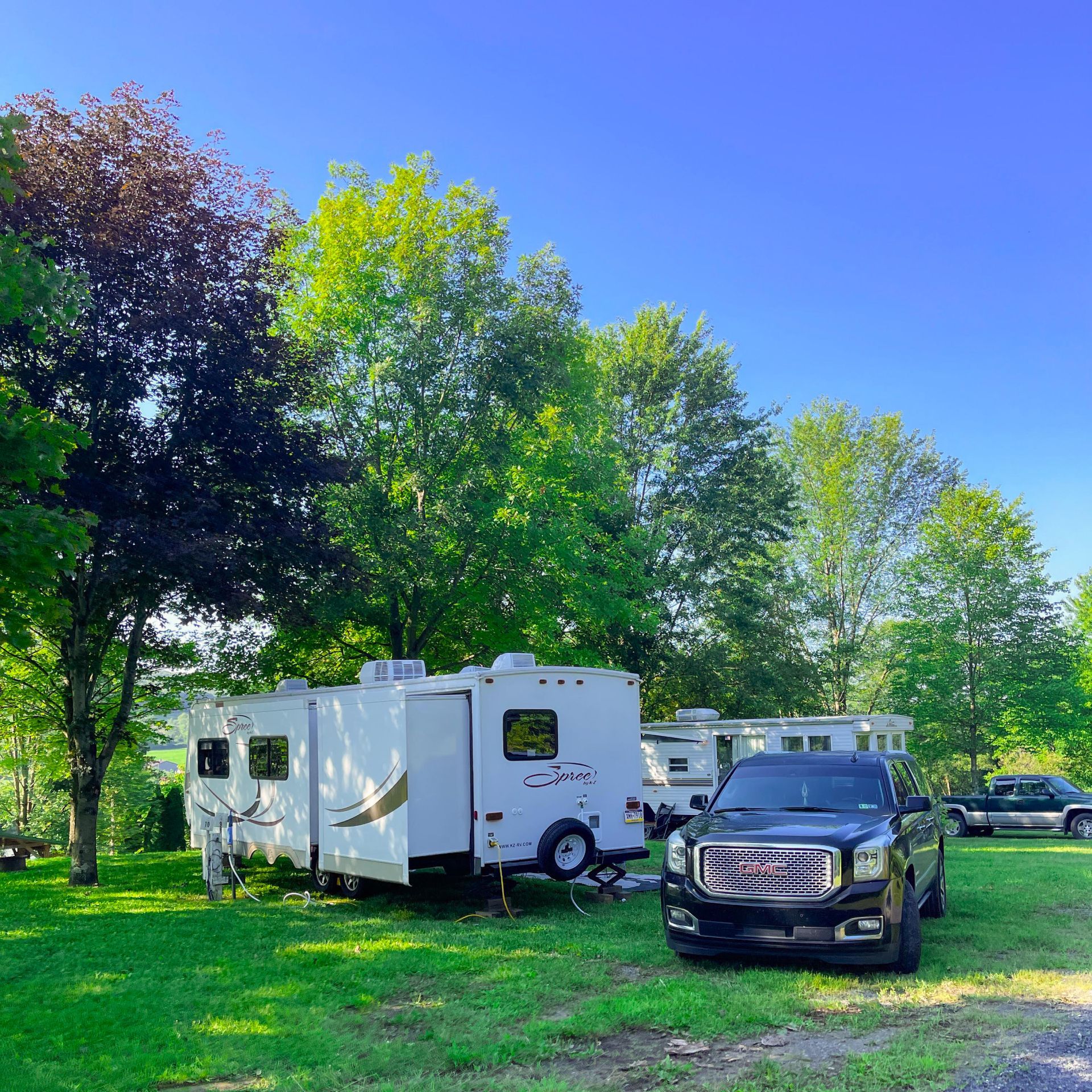 A gm truck is parked in a grassy field next to a trailer