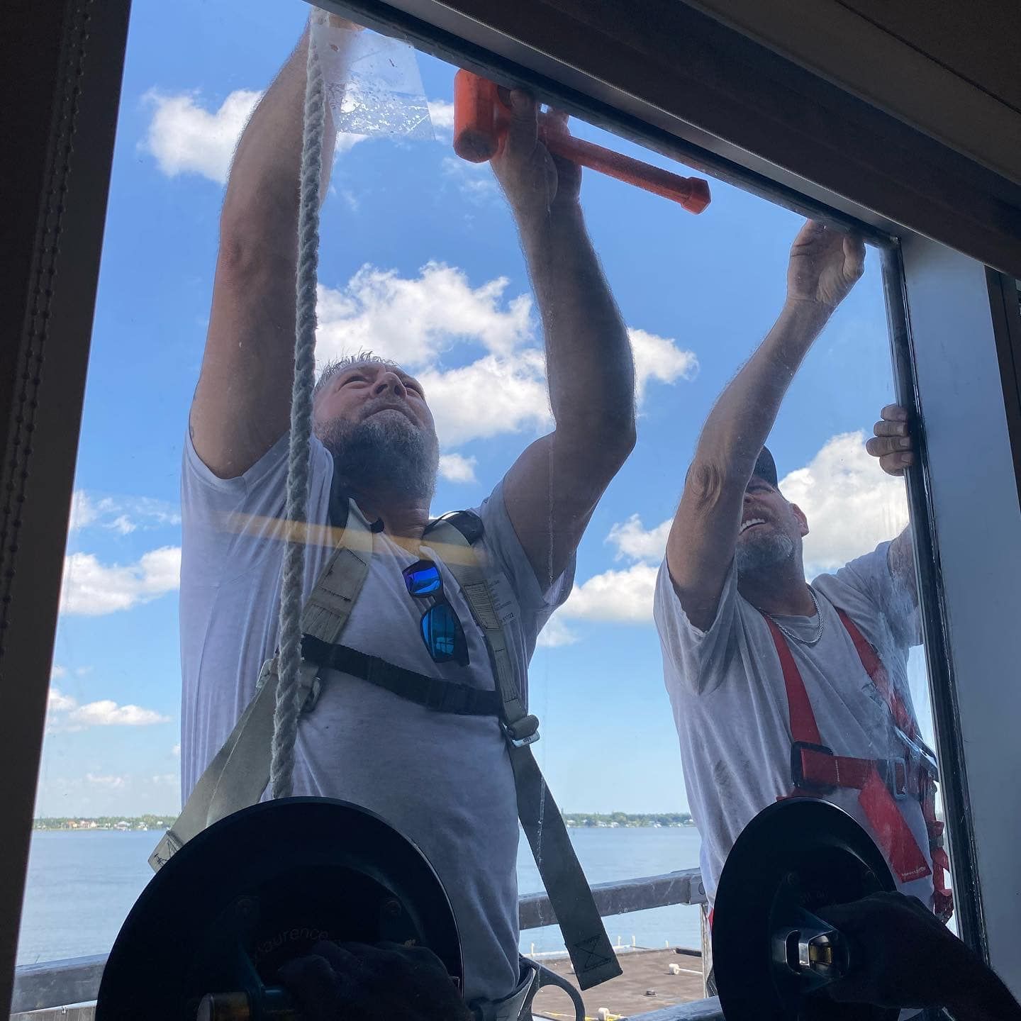 Two men are cleaning a window with a hammer