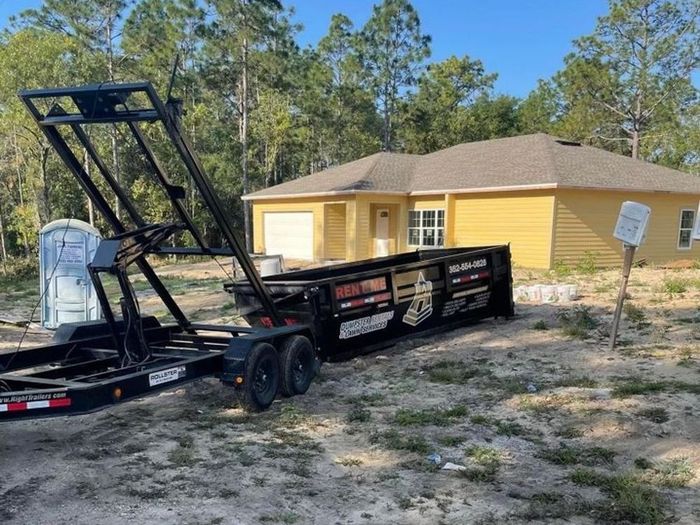 A trailer is parked in front of a yellow house.