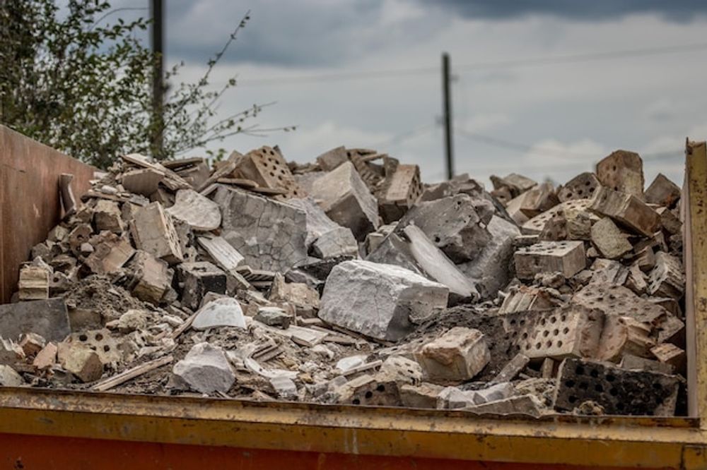 A pile of bricks is sitting on top of a dumpster.