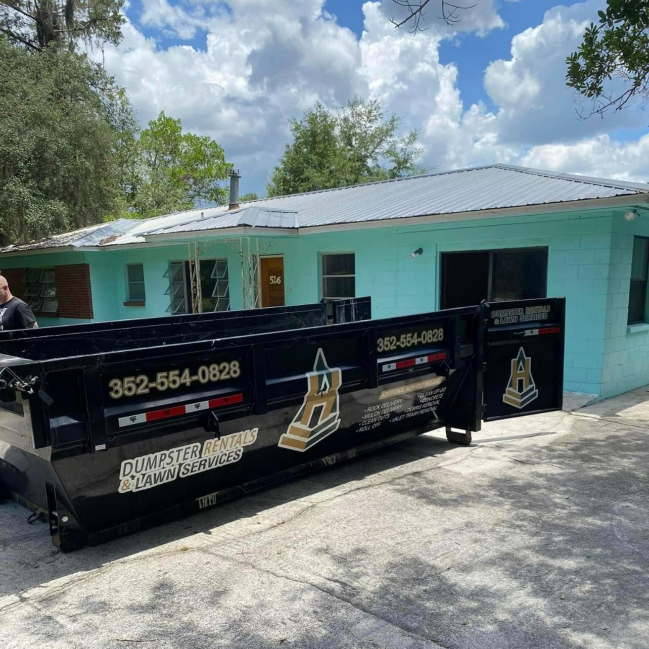 A dumpster is parked in front of a house.
