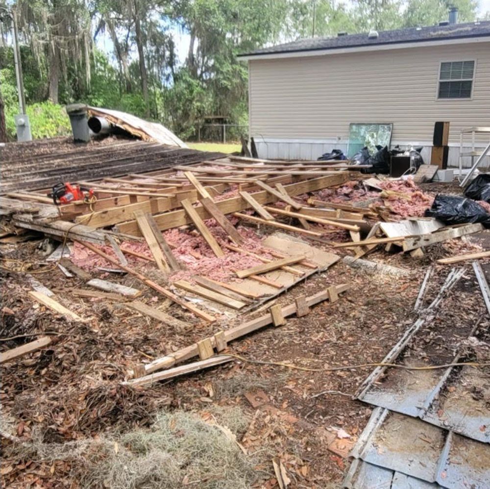 A house is being demolished and a lot of wood is laying on the ground.