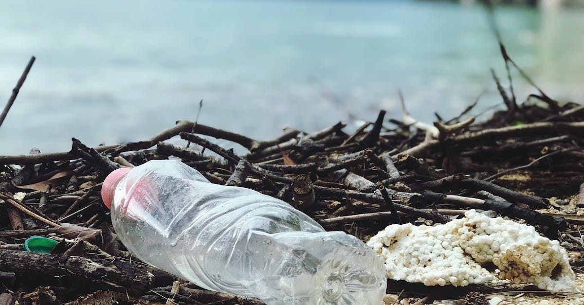 A plastic bottle is laying on the ground on the beach.
