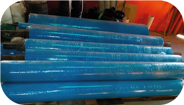 Objetos cilíndricos envueltos en azul apilados sobre una paleta de madera,
