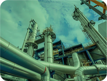 Planta industrial con tuberías y torres contra un cielo nublado.