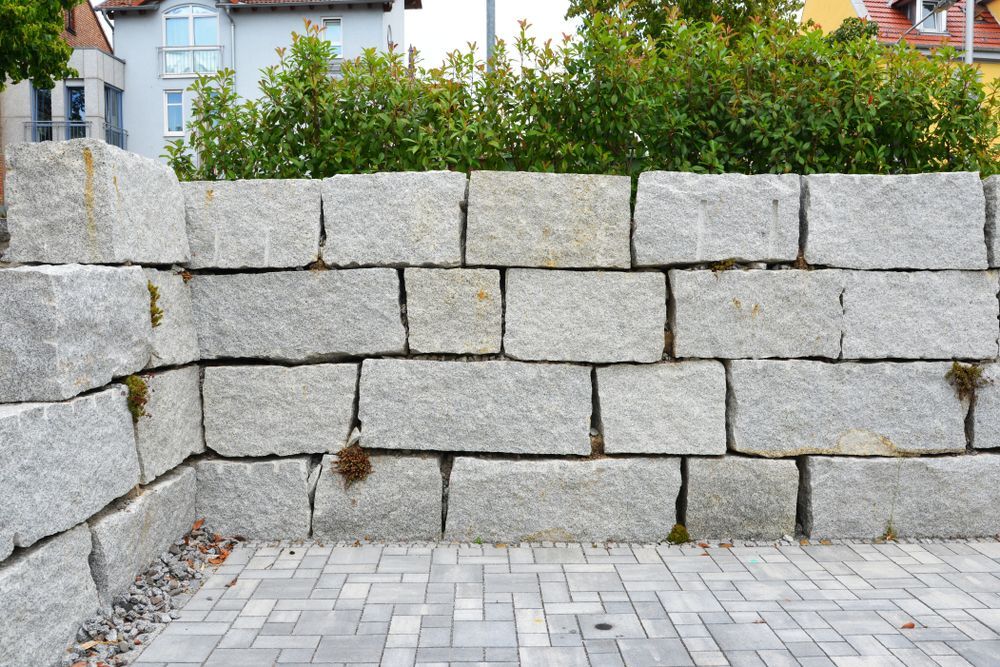 A Fence Made Of Bricks And Metal Is Surrounded By Gravel — CQ Fencing & Retaining Walls In Yeppoon, QLD