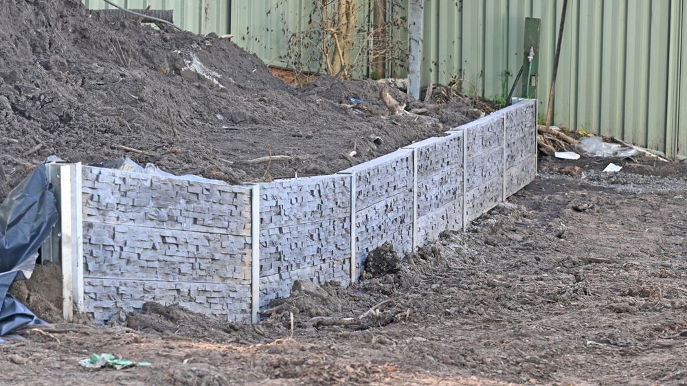 A concrete fence is being built next to a pile of dirt — CQ Fencing & Retaining Walls In Clinton, QLD