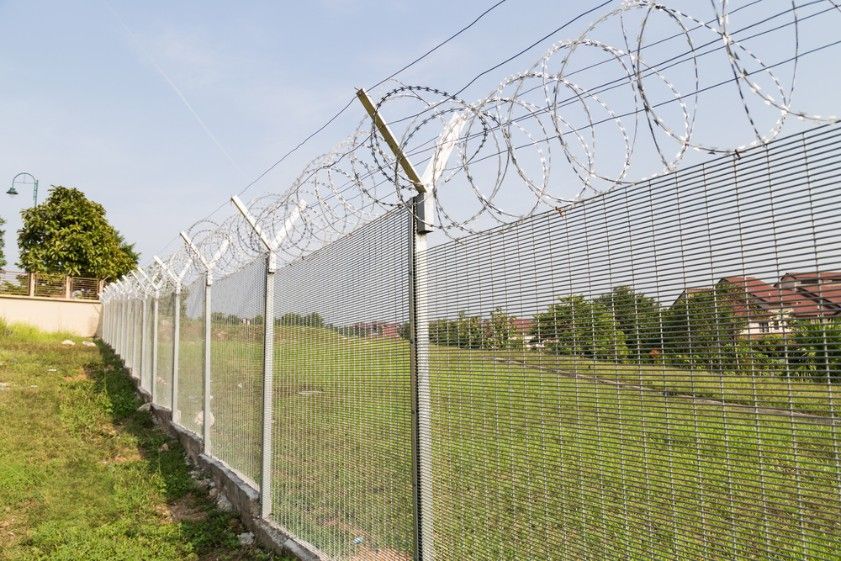 A Barbed Wire Fence Surrounds A Grassy Field — CQ Fencing & Retaining Walls In Clinton, QLD