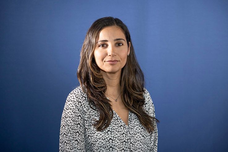 A woman is posing for a picture in front of a blue background.