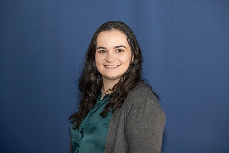 A brown dog is sitting on a blue blanket and looking up.