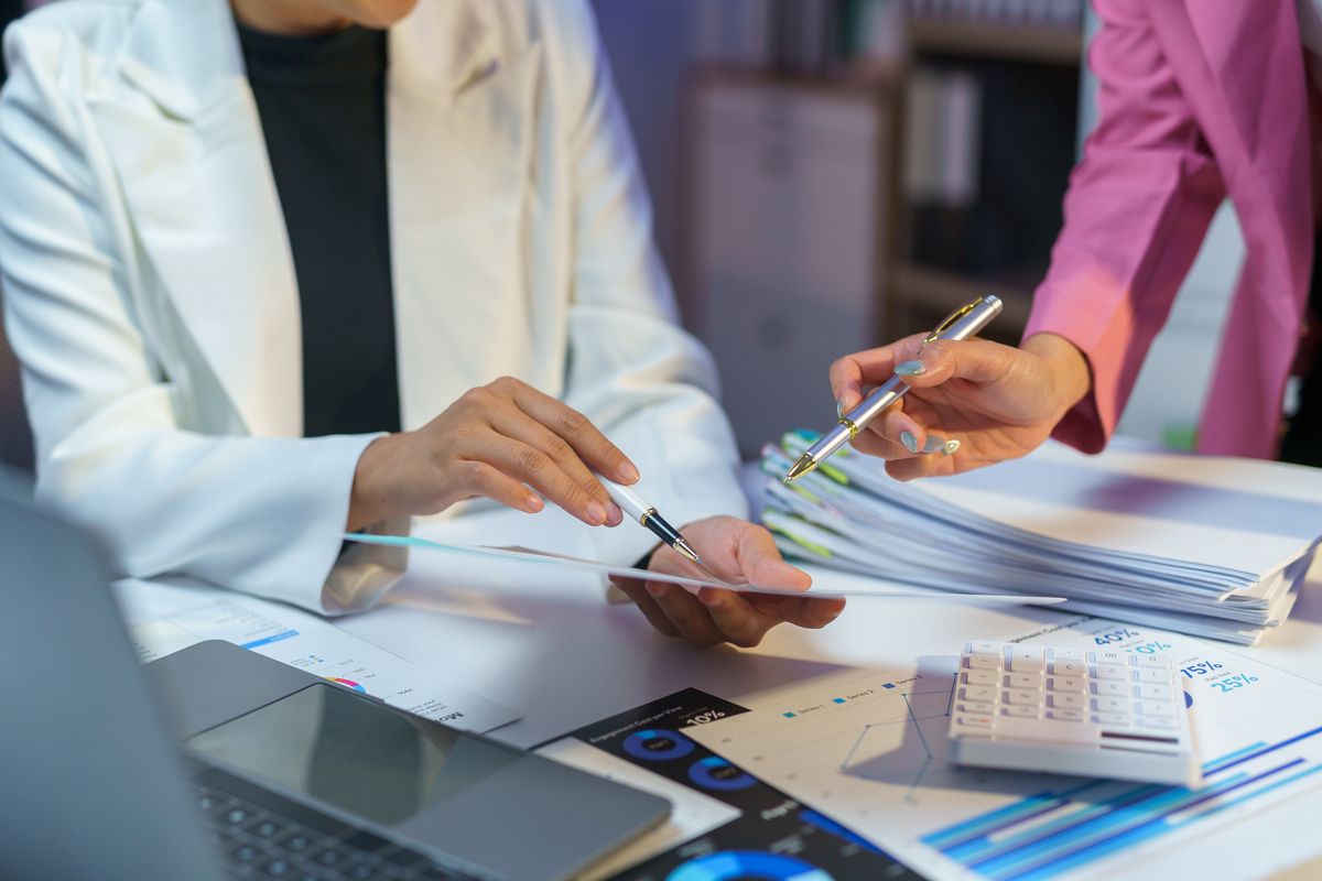 Business meeting with people signing documents and reviewing paperwork at a desk