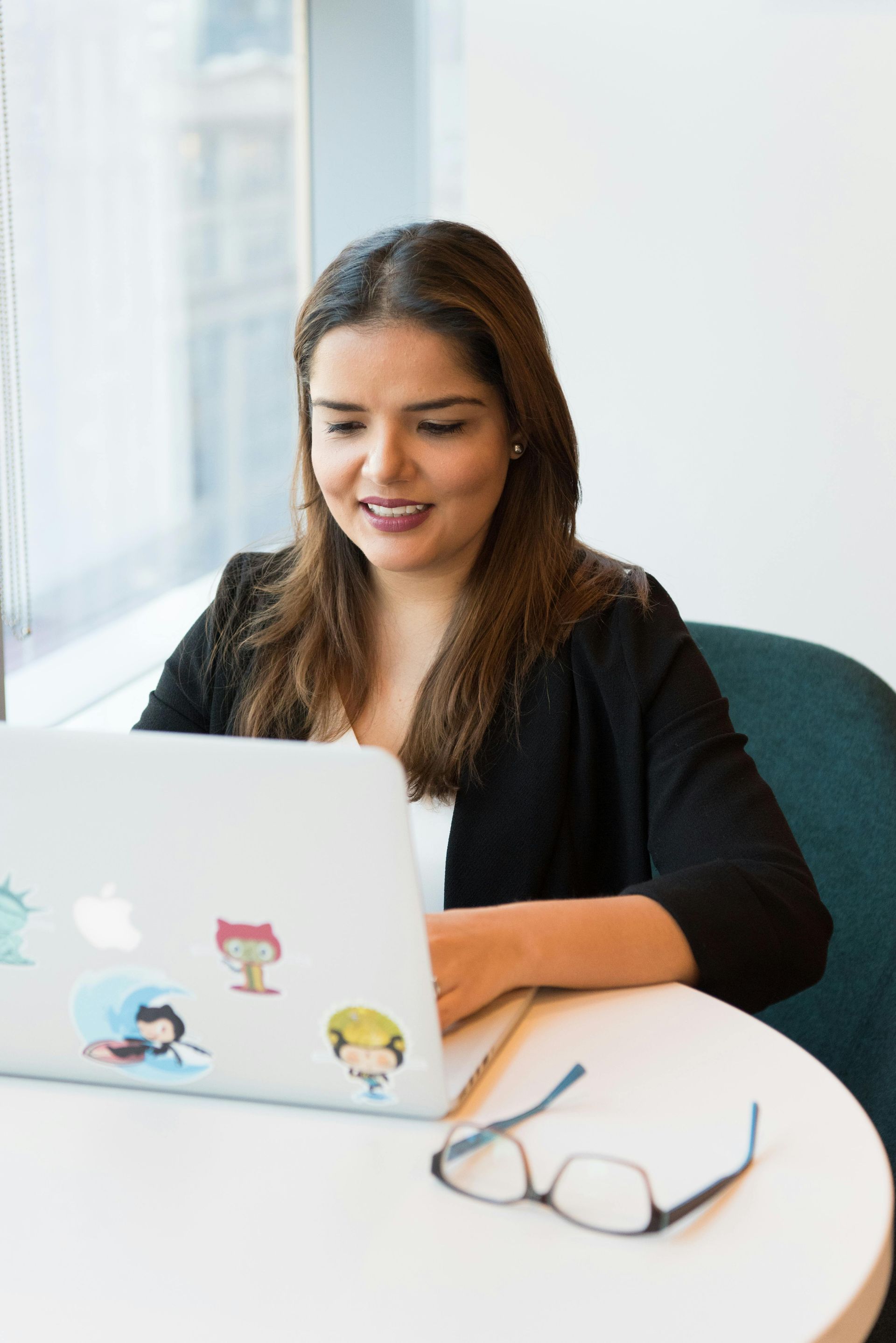 A woman is sitting at a table using a laptop computer.