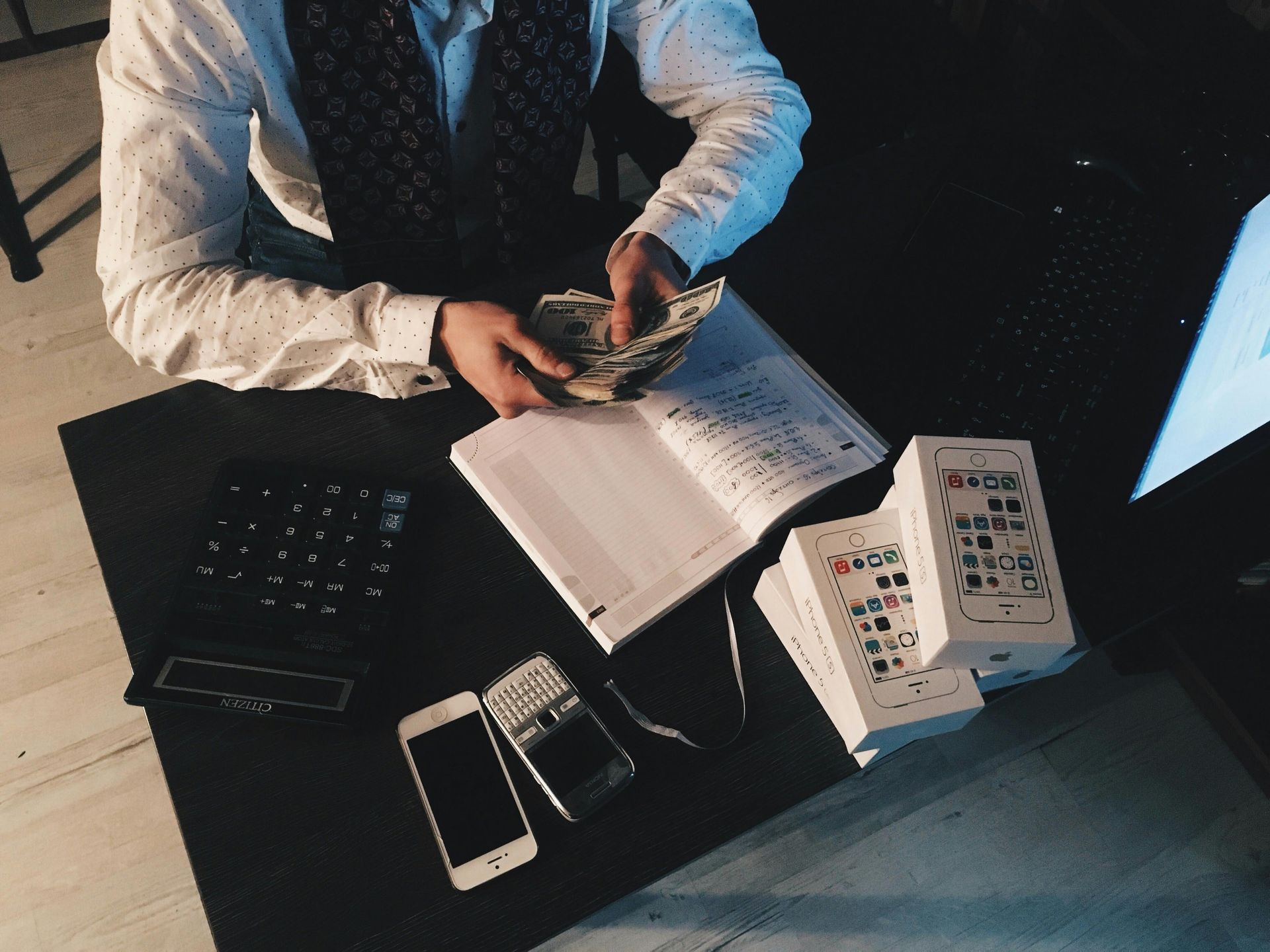 A man is sitting at a desk counting money