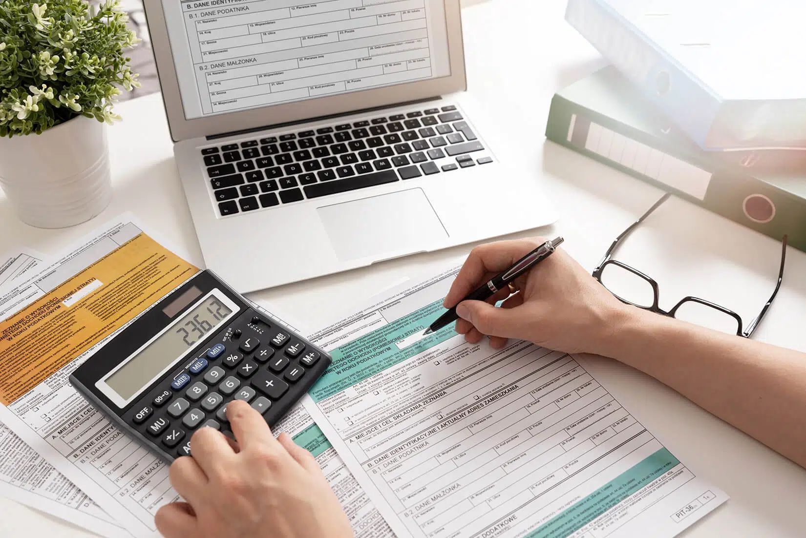 A person is using a calculator and writing on a piece of paper.
