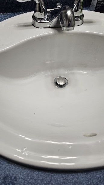 A white sink with a chrome faucet is sitting on a blue counter.