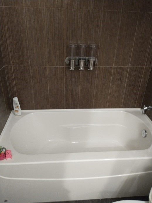 A white bathtub is sitting in a bathroom next to a toilet.