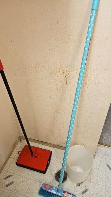 A mop , broom , and bucket are sitting on a tiled floor.