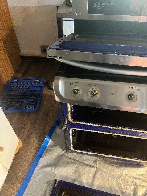 A stove with the door open is sitting on a table next to a toolbox.