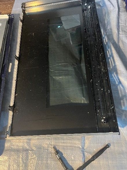 A microwave oven door is sitting on a table next to a pen.