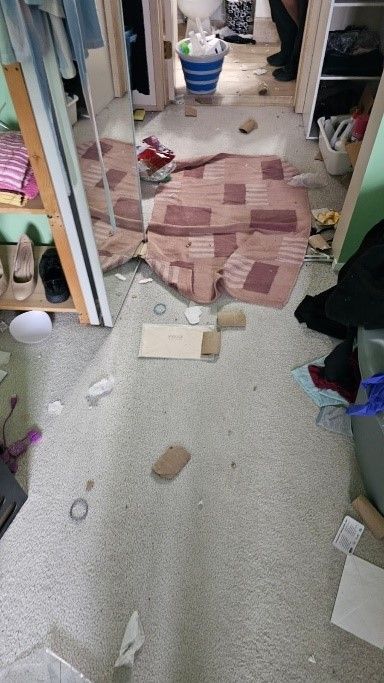 A room with a lot of trash on the floor and a box on the floor.