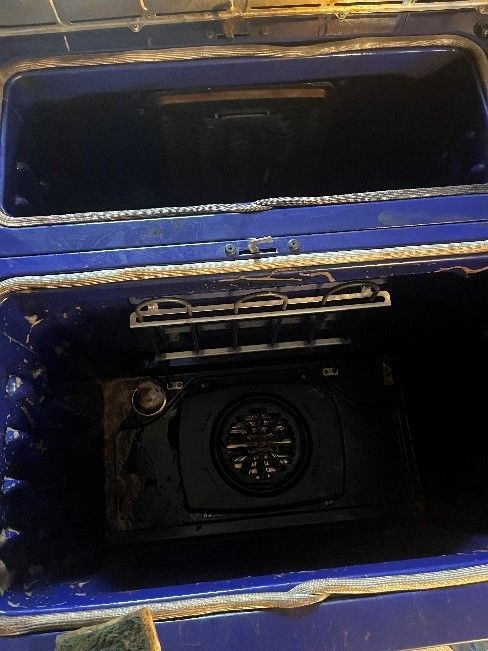 The inside of a blue oven is dirty and needs to be cleaned.