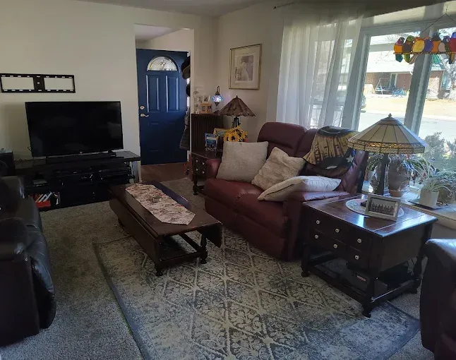 Modern house with brown siding, large windows, and a large tree in the yard.