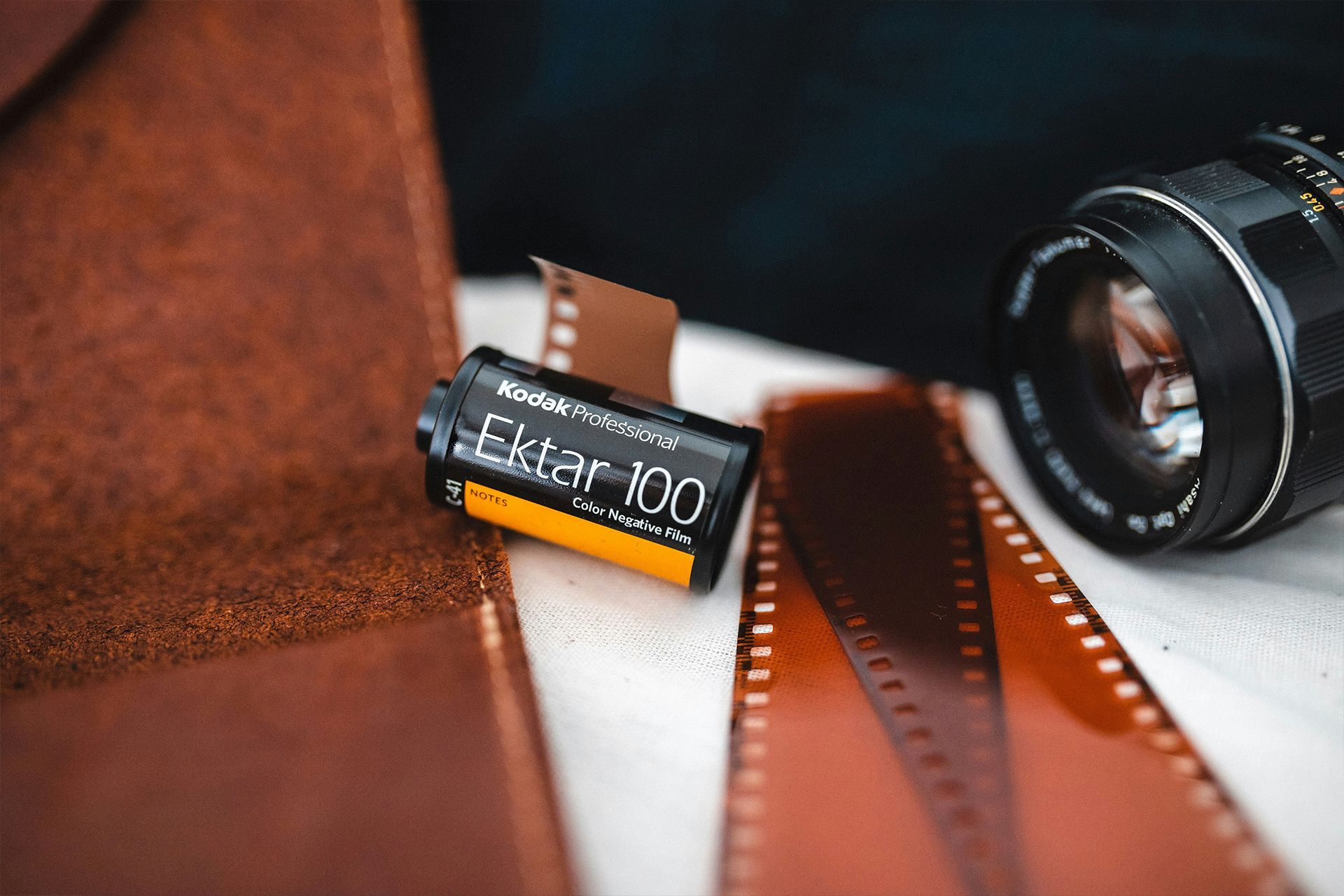 A roll of film and a camera lens are on a table.