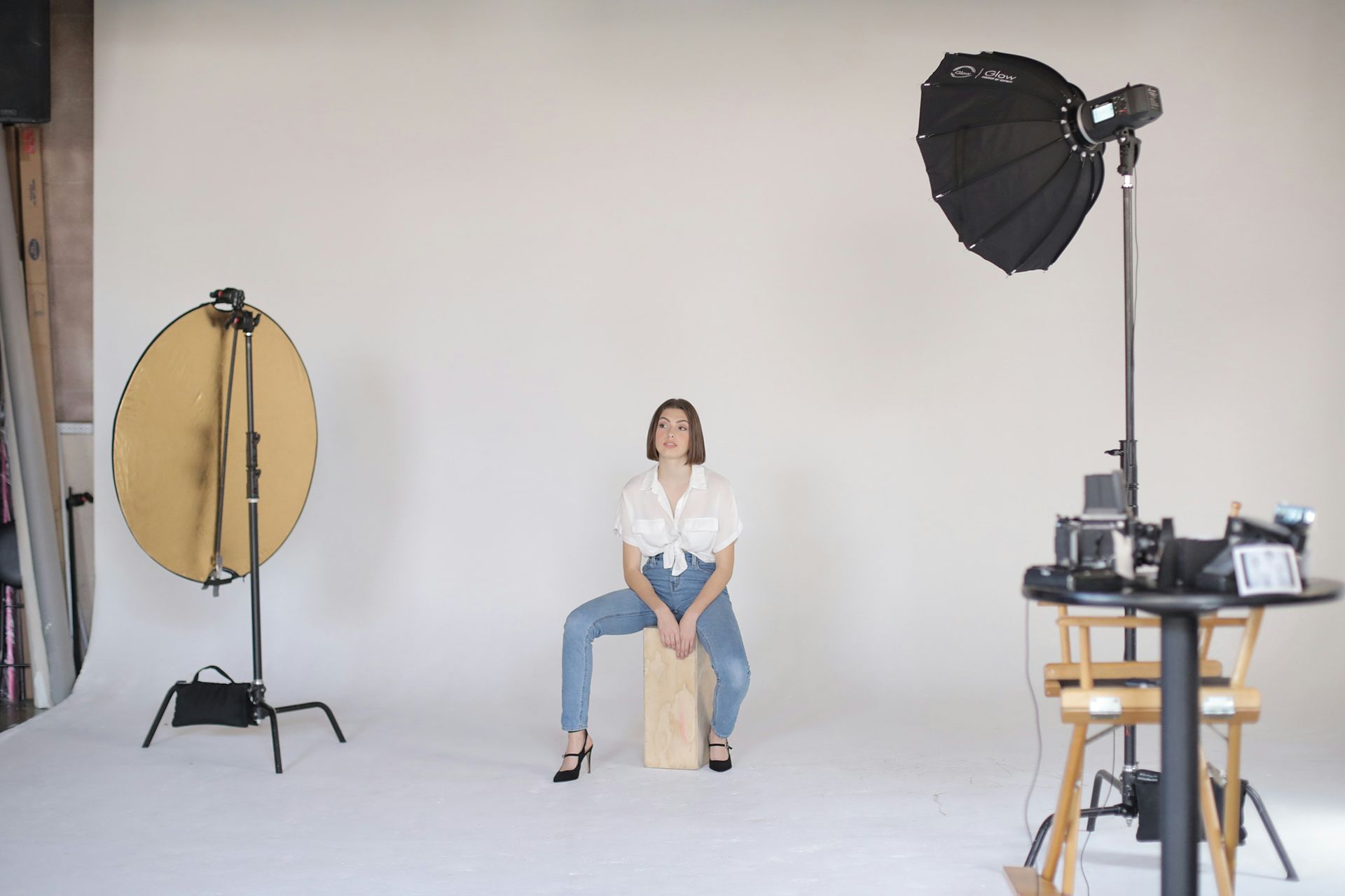 A woman is sitting on a wooden box in a photo studio.