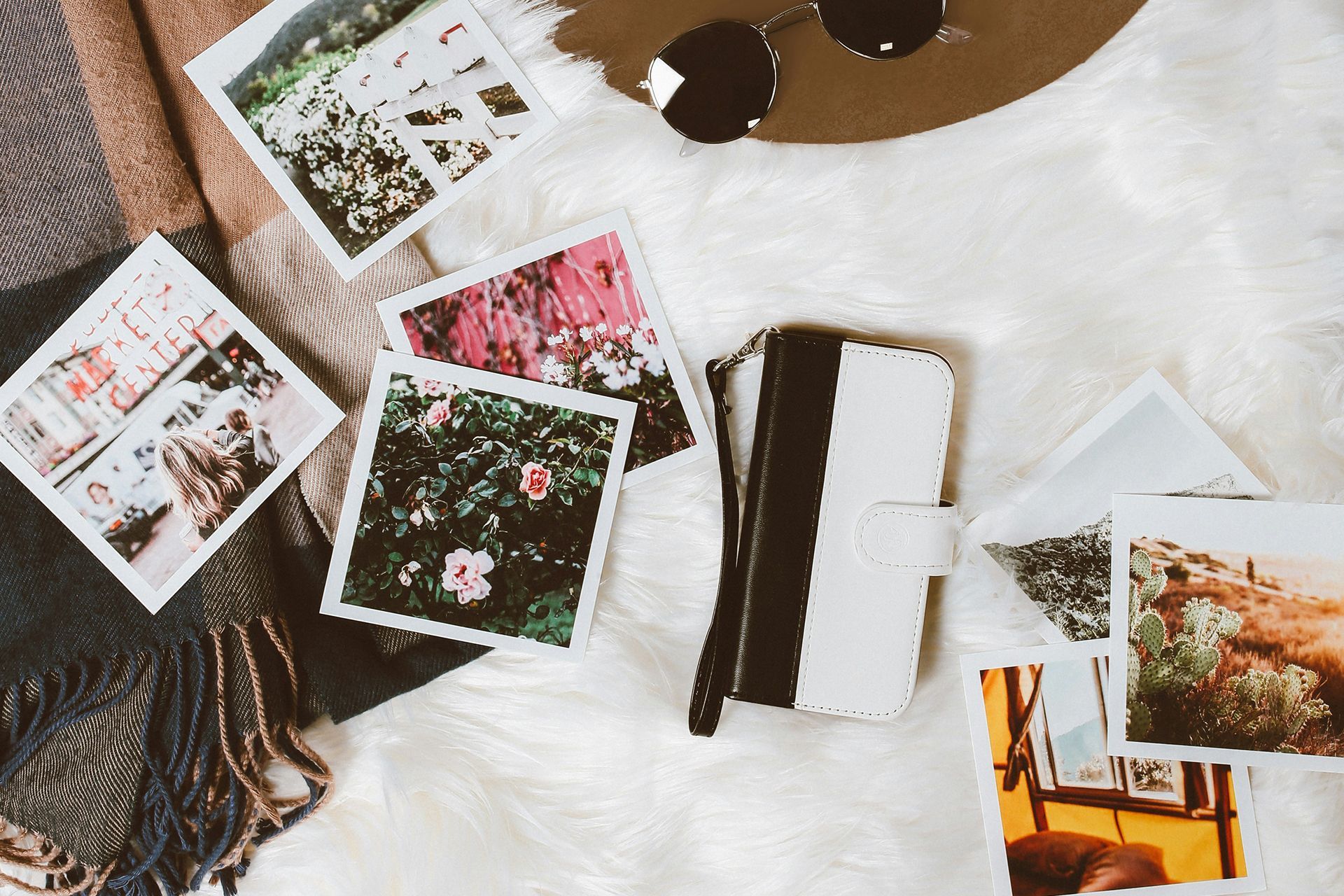 A bunch of pictures are sitting on a white blanket on a table.